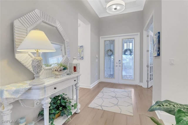 foyer with light hardwood / wood-style flooring, ornamental molding, and french doors