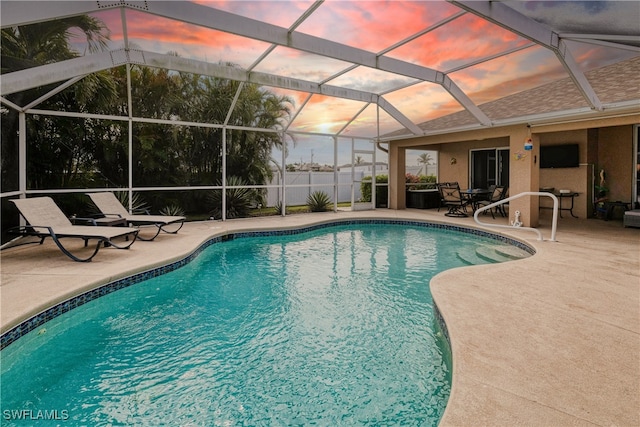 pool at dusk featuring a lanai and a patio area