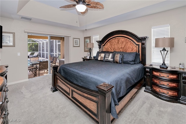 carpeted bedroom with ceiling fan, a tray ceiling, and access to outside