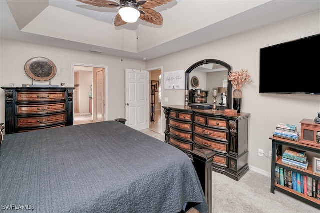 carpeted bedroom with ceiling fan and a raised ceiling