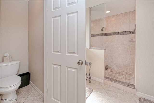 bathroom featuring tiled shower, toilet, and tile patterned flooring