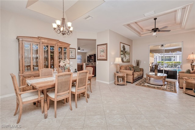 dining room with ceiling fan with notable chandelier and a tray ceiling