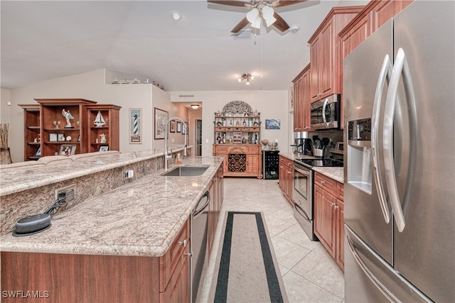 kitchen featuring light tile patterned floors, appliances with stainless steel finishes, light stone countertops, vaulted ceiling, and sink