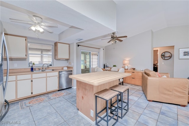 kitchen featuring sink, a breakfast bar area, appliances with stainless steel finishes, a center island, and vaulted ceiling