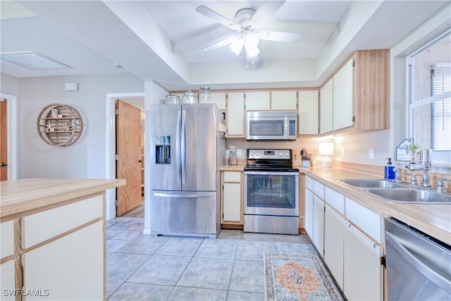 kitchen with light tile patterned flooring, appliances with stainless steel finishes, sink, and white cabinets