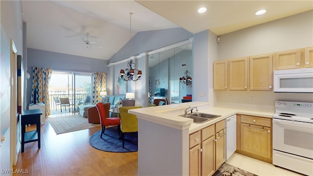 kitchen featuring vaulted ceiling, kitchen peninsula, sink, white appliances, and light brown cabinetry