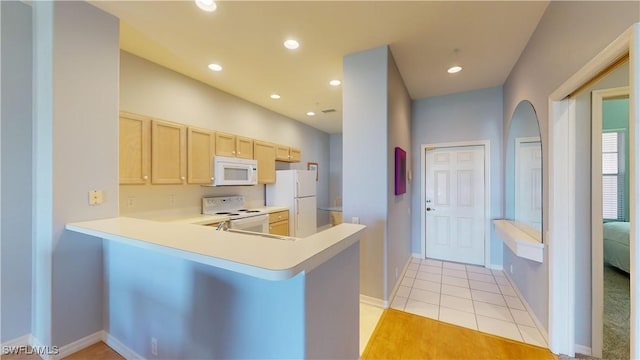 kitchen with white appliances, light tile patterned floors, kitchen peninsula, and light brown cabinets