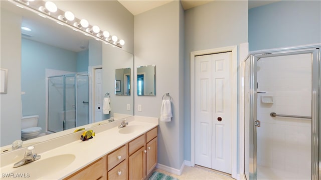 bathroom featuring toilet, a shower with door, tile patterned floors, and vanity