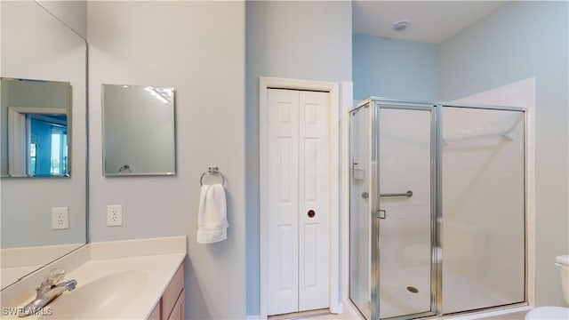 bathroom featuring a shower with door, toilet, and vanity