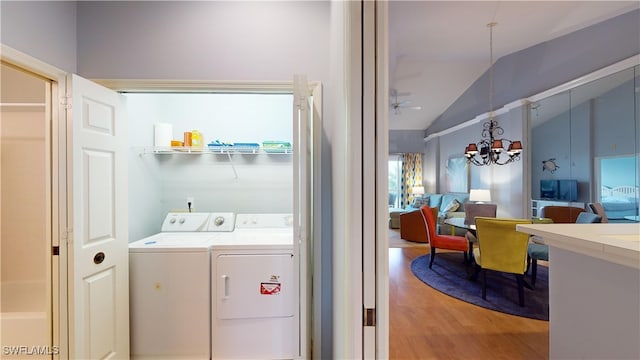 clothes washing area with washer and dryer, ceiling fan with notable chandelier, and wood-type flooring