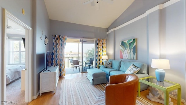 living room with ceiling fan, light hardwood / wood-style flooring, and vaulted ceiling