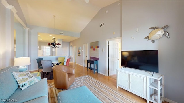 living room featuring lofted ceiling, a notable chandelier, and light hardwood / wood-style floors