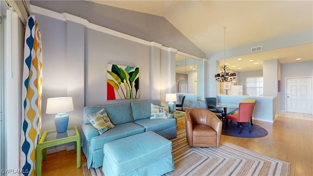 living room with hardwood / wood-style flooring, lofted ceiling, and an inviting chandelier