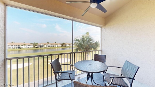 sunroom / solarium with ceiling fan and a water view