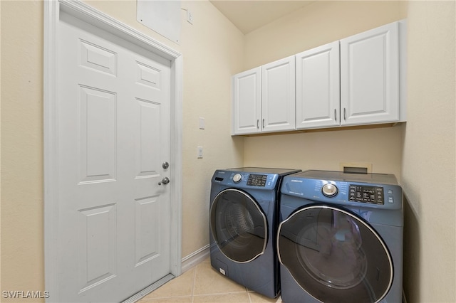 clothes washing area with cabinets, light tile patterned flooring, and washer and clothes dryer