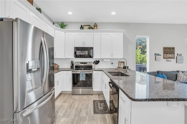 kitchen with sink, white cabinetry, dark stone countertops, black appliances, and light wood-type flooring