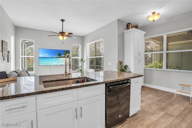 kitchen featuring sink, white cabinetry, light hardwood / wood-style flooring, dark stone countertops, and black dishwasher