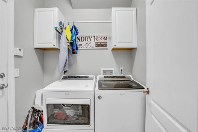 clothes washing area with cabinets and separate washer and dryer