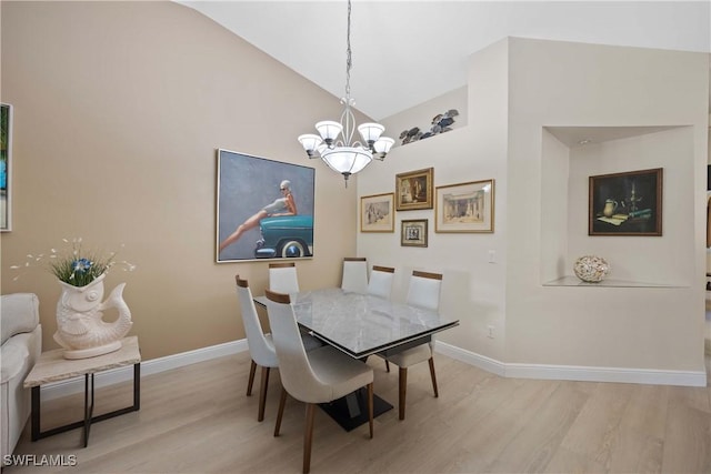 dining room with light hardwood / wood-style flooring, vaulted ceiling, and a notable chandelier