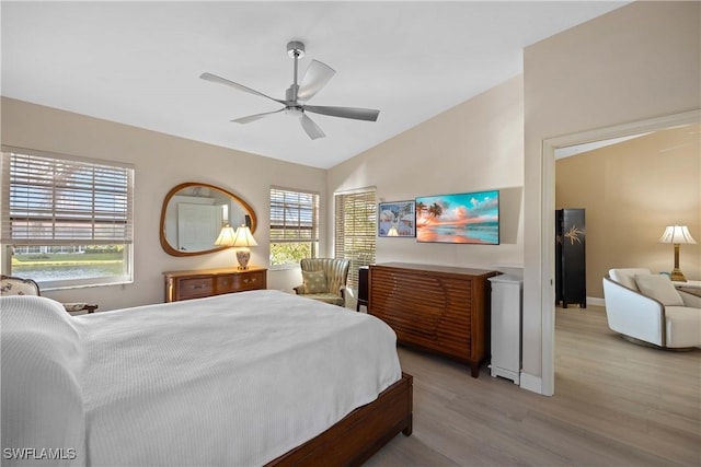 bedroom with ceiling fan, vaulted ceiling, and light hardwood / wood-style floors