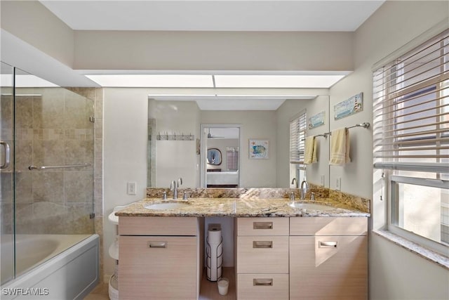 bathroom featuring combined bath / shower with glass door and vanity