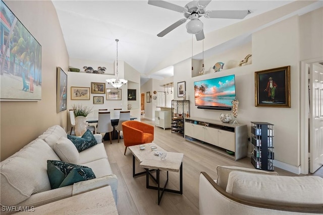 living room featuring vaulted ceiling, ceiling fan with notable chandelier, and light hardwood / wood-style flooring