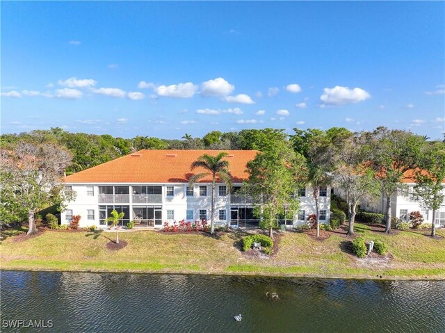 back of house with a water view and a yard