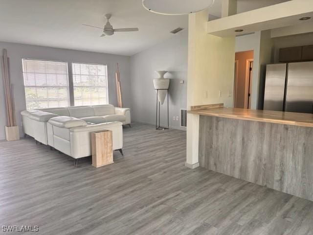 unfurnished living room featuring vaulted ceiling, dark wood-type flooring, and ceiling fan