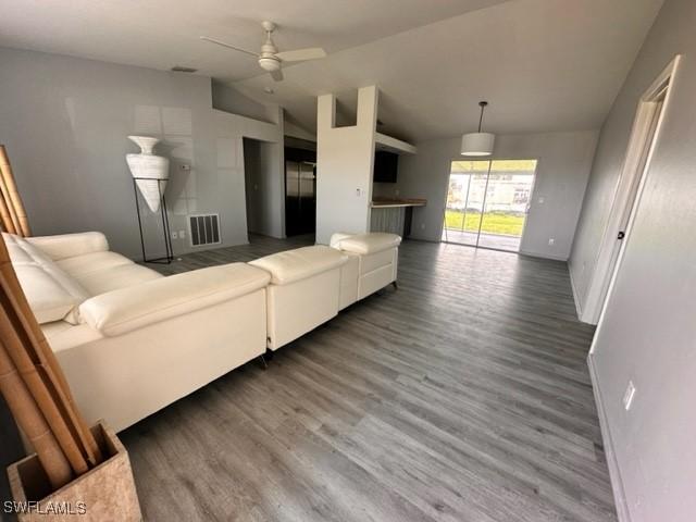 living room featuring hardwood / wood-style flooring, ceiling fan, and vaulted ceiling