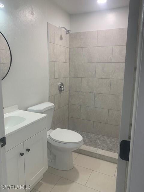 bathroom featuring a tile shower, tile patterned floors, vanity, and toilet