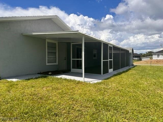 rear view of house with a yard, a sunroom, and a patio area