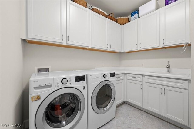 laundry area with cabinets, sink, washing machine and dryer, and light tile patterned flooring