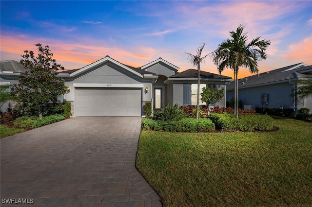 ranch-style home featuring a garage and a lawn