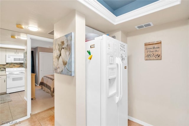 kitchen with light tile patterned flooring, white cabinetry, tasteful backsplash, and white appliances