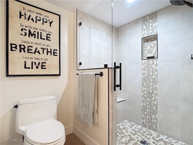 bathroom featuring toilet and a shower with door