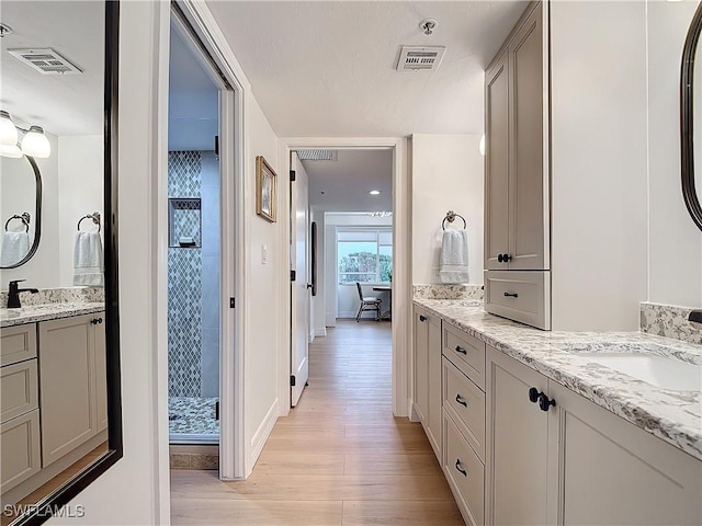 bathroom featuring vanity, hardwood / wood-style flooring, and tiled shower