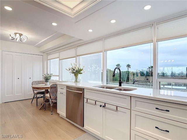 kitchen with white cabinetry, stainless steel dishwasher, light hardwood / wood-style floors, and sink