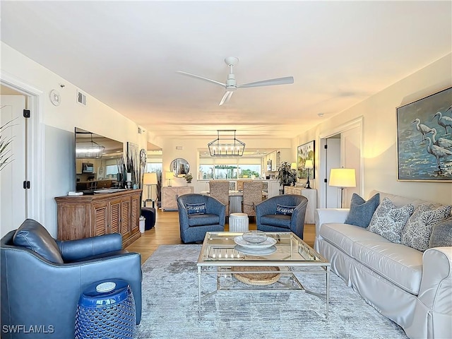 living room with wood-type flooring and ceiling fan with notable chandelier