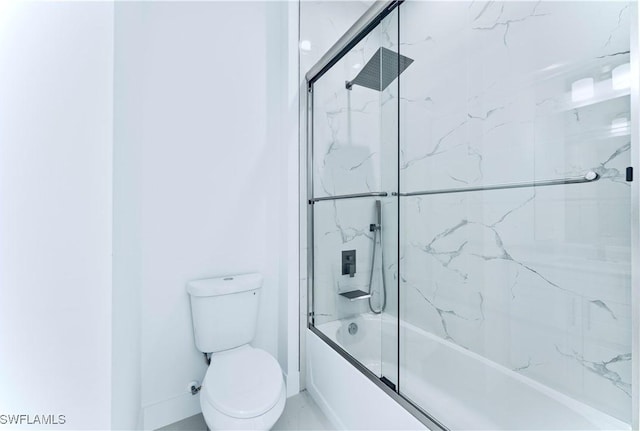 bathroom with toilet and shower / bath combination with glass door