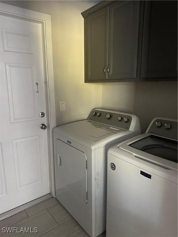 laundry area featuring light tile patterned floors, cabinets, and washer and dryer