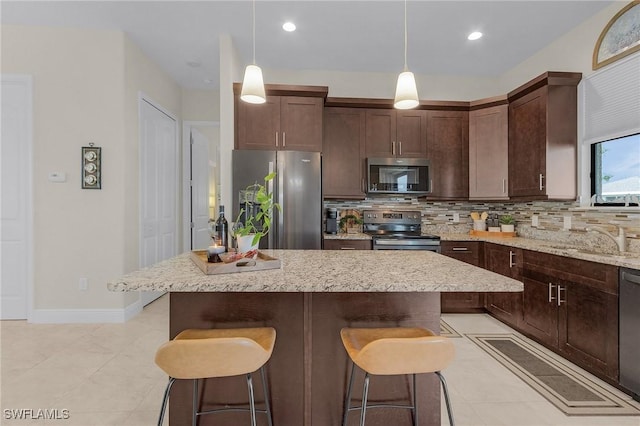 kitchen featuring appliances with stainless steel finishes, sink, a center island, and decorative light fixtures