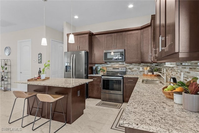 kitchen with pendant lighting, appliances with stainless steel finishes, a center island, sink, and a breakfast bar area