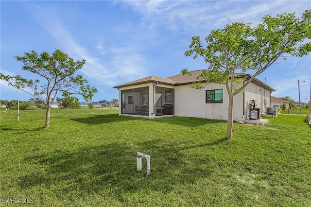 back of property featuring a sunroom, a lawn, and central AC