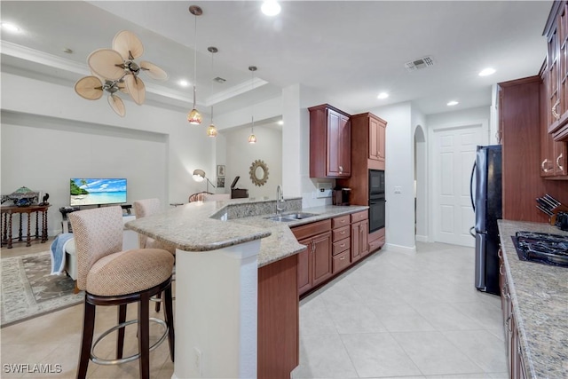 kitchen featuring a kitchen bar, kitchen peninsula, a raised ceiling, sink, and black appliances