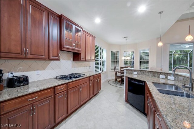 kitchen featuring decorative light fixtures, black dishwasher, sink, light stone counters, and stainless steel gas stovetop