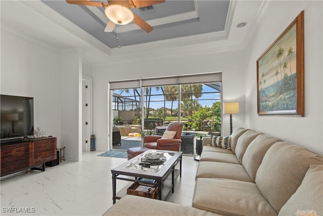 living room with ceiling fan, a tray ceiling, and crown molding