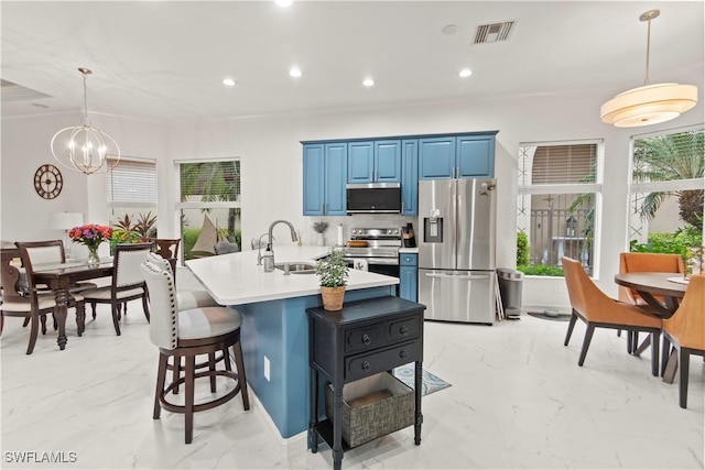 kitchen featuring sink, appliances with stainless steel finishes, hanging light fixtures, a kitchen breakfast bar, and blue cabinets