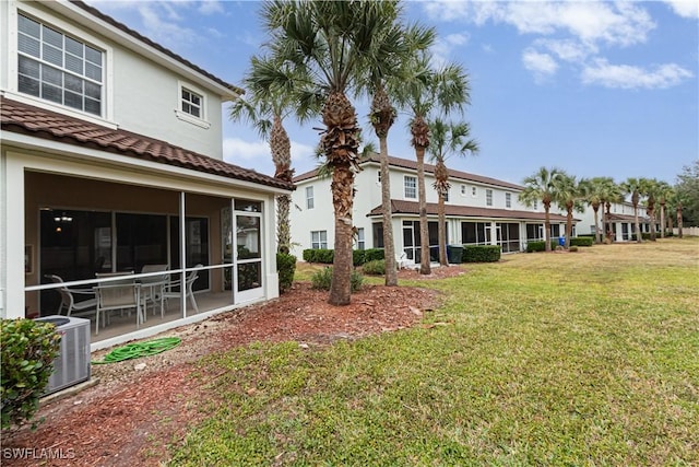 back of property featuring central AC unit, a patio area, a yard, and a sunroom