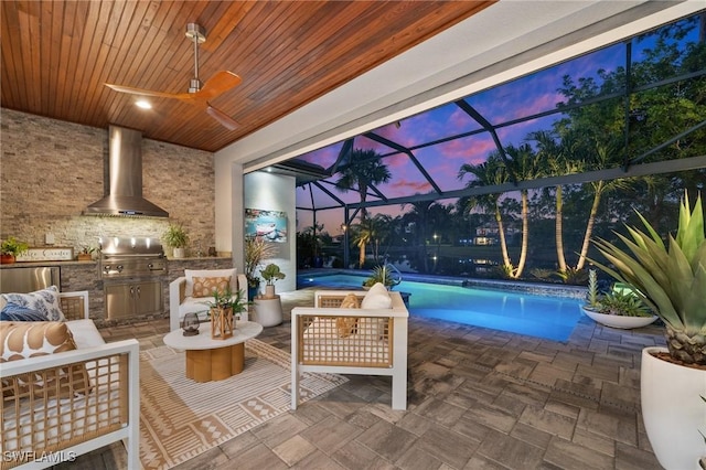 patio terrace at dusk with exterior kitchen, a lanai, an outdoor hangout area, and grilling area