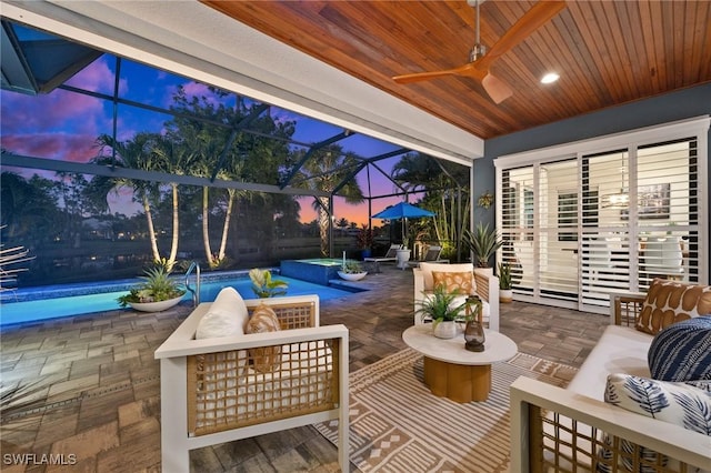 patio terrace at dusk featuring ceiling fan, an outdoor living space, and glass enclosure